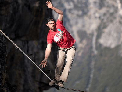 man-balance-red-cap-tightrope-mountain.png